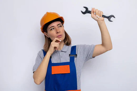 Woman thinking about installation in garage with wrench in one hand